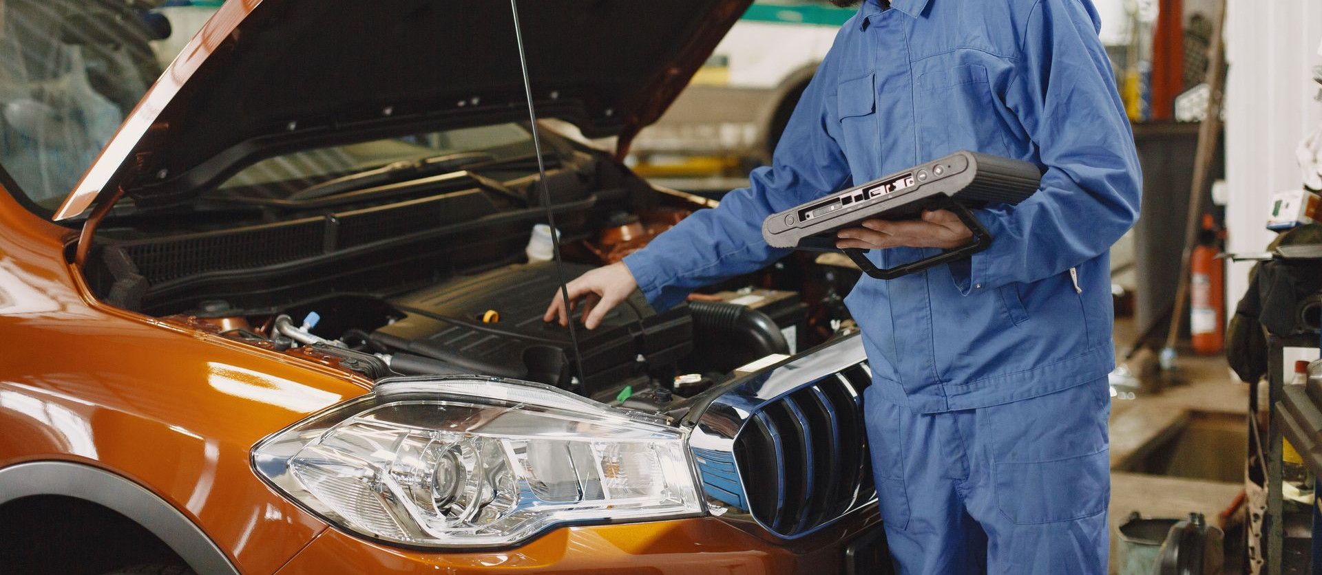 Skilled mechanic working on car engine diagnostics in a modern garage.